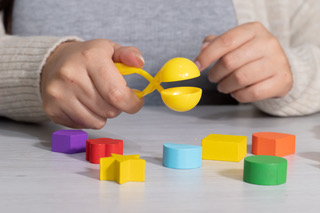 Child's hands using a tool to pick up a ball