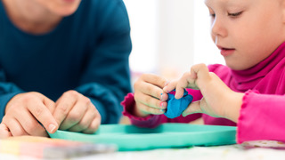 A therapist working with a young girl on a hands-on fine motor activity