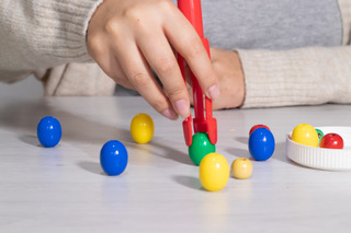 Child using tongs to sort colorful balls