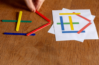 Child copying a pattern with colored sticks